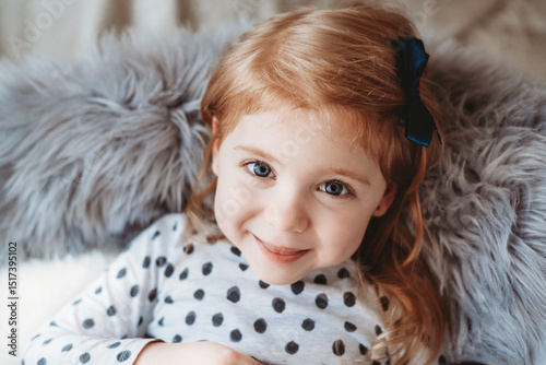 Cute red haired girl sitting in a chair and smiling at the camera photo