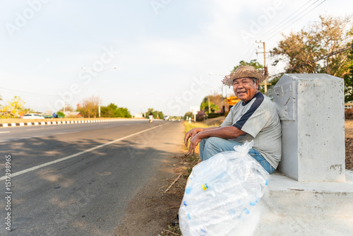Elderly Thai man resting roadside with collected plastic bottles