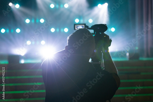Cameraperson Recording Scene with Spotlights at Event Venue