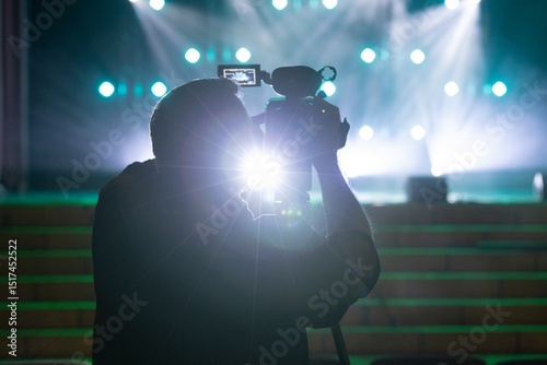 Cameraperson Recording Scene with Spotlights at Event Venue