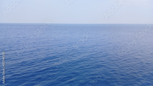 Fototapeta Naklejka Na Ścianę i Meble -  Calm and expansive view of the ocean under clear blue sky on a sunny day.