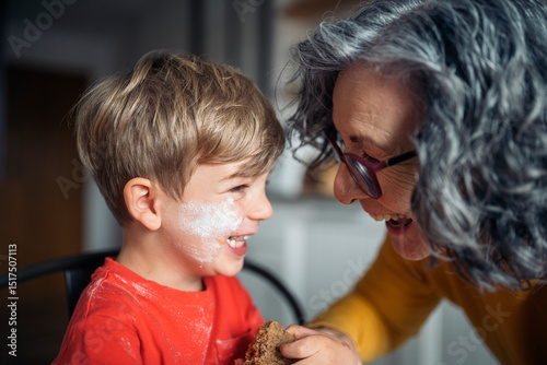 Grandmother sharing a loving moment with grandson while baking photo