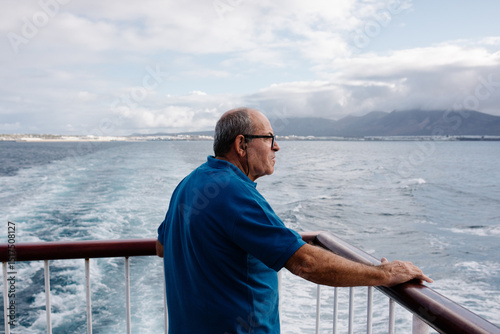 Retired man resting against the railing at the rear of a boat