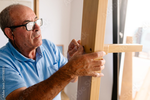 Retired man installing screws to assemble new furniture photo