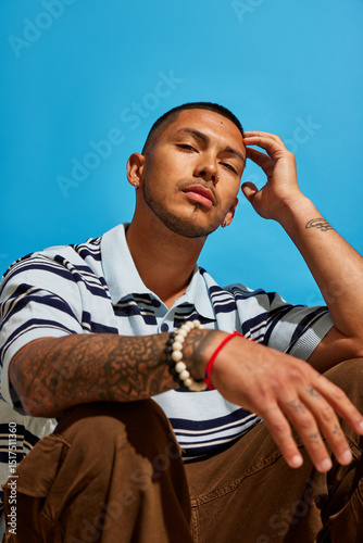 Model poses against bright blue background in casual attire