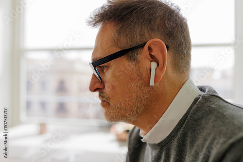 Businessman wearing wireless earbuds concentrating on work photo
