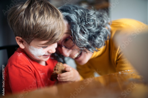 Grandmother and grandson sharing a sweet treat in the kitchen photo