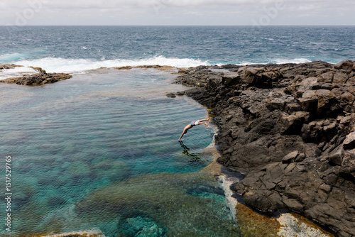 Person diving into a shallow natural pool beside the ocean photo