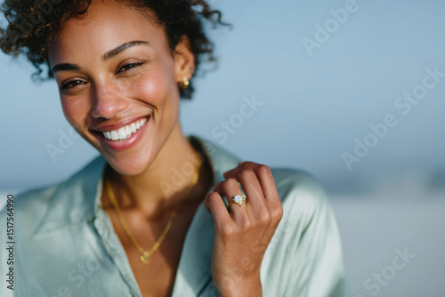 Beautiful smiling woman showing her engagement ring on the beach