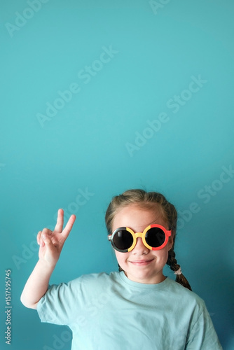 Cheerful girl 6-8 years old on a emerald color background with a gradient spot for text - vertical banner