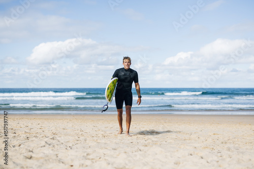 Surfer is walking out of the ocean after surfing some waves