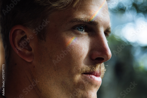 Rainbow reflecting on young man's face creating colorful effect