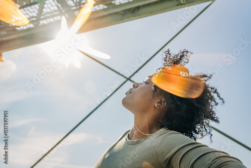 Woman basking in sunlight with head tilted back in joy photo