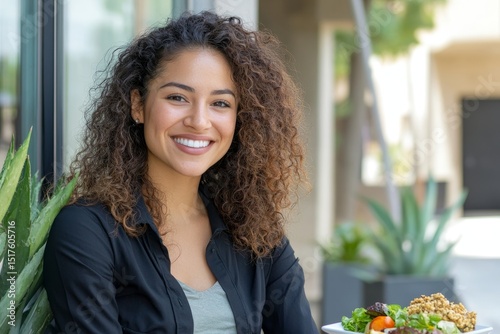 Young Hispanic businesswoman with curly hair enjoying a lunch break outside her office, radiating professionalism and joy