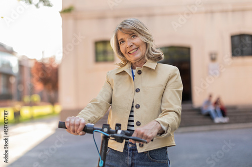 Teacher smiling while standing with electric scooter outdoors photo