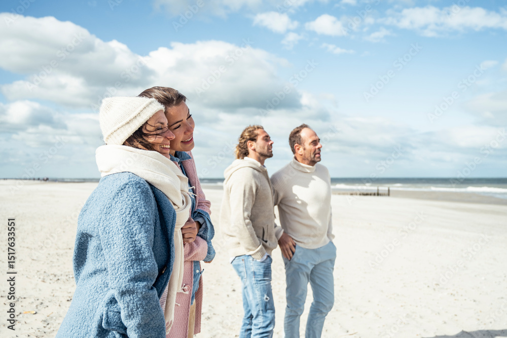 Group of adult friends standing and talking on coastal beach Group of adult friends standing and talking on coastal beach