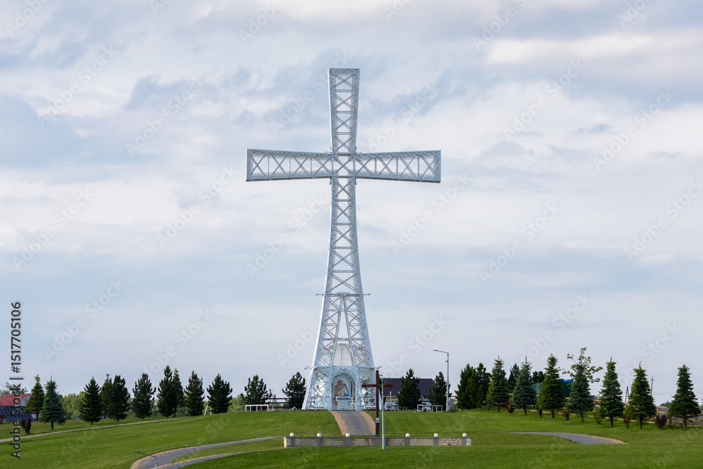 Obraz premium People walk a winding path toward the massive hilltop cross, surrounded by manicured lawns and religious symbolism in the Ukrainian countryside