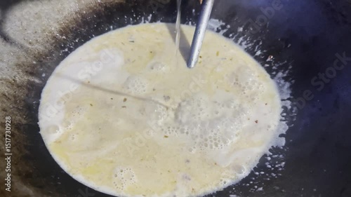 Asian cook is cooking in thai kitchen in local traditional country style, preparing sizzling thai green curry paste being stir fried in traditional wok to cook thai food green curry popular worldwide