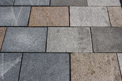 Texture of brown and gray square paving tile. Pattern of sidewalk tiles in the street. Concrete pavers close up background.	