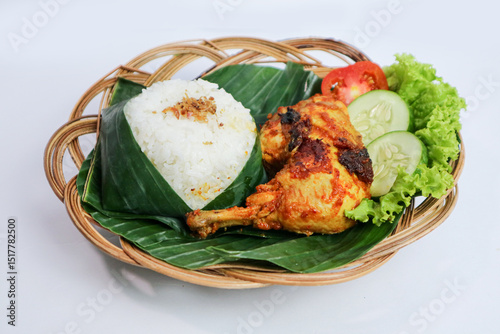 Ayam bakar or roasted chicken on banana leaf shoot at a rustic wooden background. Ayam bakar is a indonesian dish. Ayam bakar literally means 