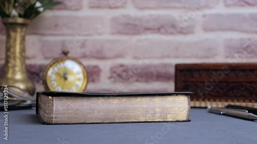 Bible falling for study on gray table with glasses and clock in the morning. Preparation for communion and worship concept. Slow motion