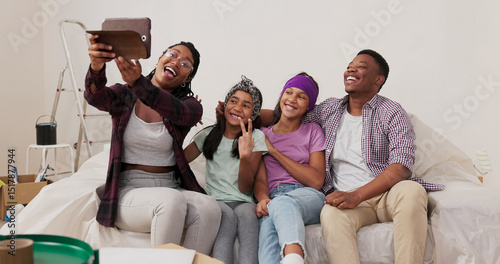 A joyful couple with two daughters sits on the sofa in their renovated apartment. The woman holds a tablet, trying to take a selfie with her family, laughing at the failed attempt.