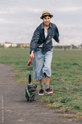 Teenager girl running with dog in a park during daytime