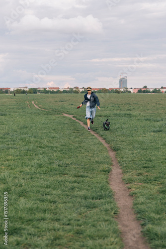 Young girl running with his dog in a large park in Berlin