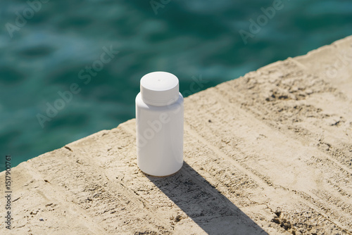 White mockup container with tablets placed on seaside rocks on sea background. Natural healing, dietary support, eco-pharmacy, clean healthcare concept.