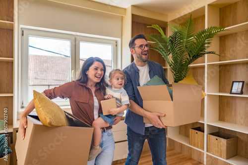 Happy young family with child enjoying new home after moving in – unpacking boxes, relaxing in living room, spending time together in kitchen, celebrating new beginning. Man, woman and daughter.