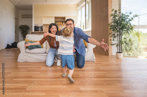 Happy young family with child enjoying new home after moving in – unpacking boxes, relaxing in living room, spending time together in kitchen, celebrating new beginning. Man, woman and daughter.