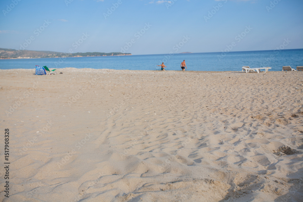 Obraz premium Serene beach with soft sand, clear sky, and gentle waves—perfect for travel ads, wellness blogs, and summer lifestyle campaigns.
