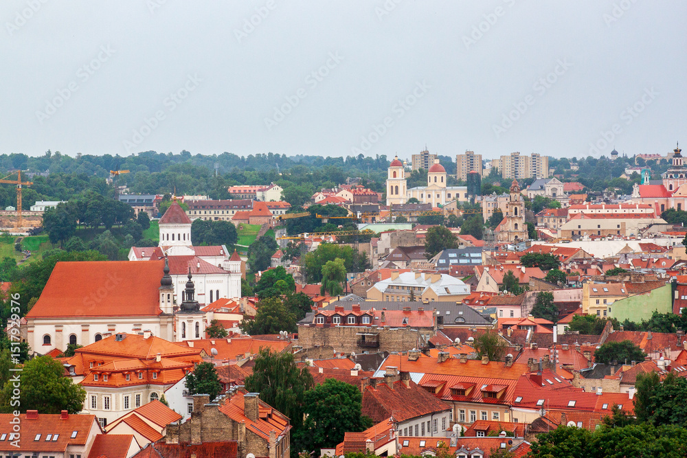 Obraz premium Cityscape of Vilnius, Lithuania from viewpoint in a summer cloudy day. View of the old town with orange tile roofs. Famous tourist destination. Travel photography.