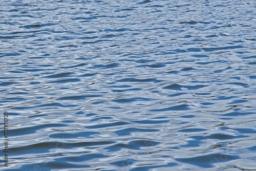 dark blue rippling water surface with light reflections background 