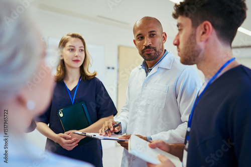 Medical team discussing patient charts in hospital corridor photo