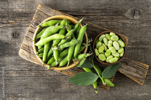 Fresh broad beans with pod in bowl on wooden background, healthy food