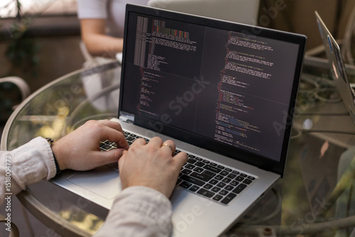 Three software developers brainstorming in a modern office. Team coding session with laptops showing code, planning web development and design. Tech startup environment and teamwork