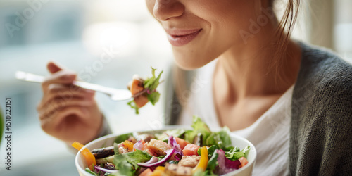 Woman enjoys a colorful salad, showcasing healthy eating and wellness lifestyle choices.  Image depicts freshness and nutritious meal