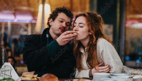 Fotografi A young couple enjoys a meal together at a cozy restaurant, sharing moments of connection and warmth