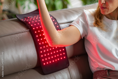 Red light therapy pad on the elbow reduces pain and inflammation from injuries or tendonitis. It boosts blood flow and aids tissue healing, enhancing mobility and comfort with non invasive care photo