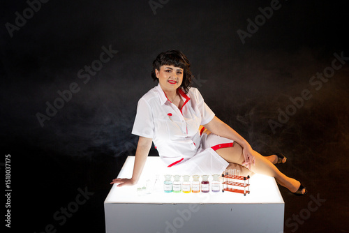Teacher in a lab coat on a black background with a set of chemical compounds and various glass test tubes