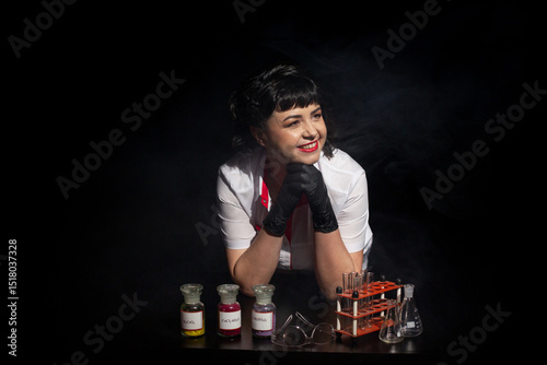 Teacher in a lab coat on a black background with a set of chemical compounds and various glass test tubes