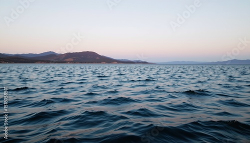 open lake with gentle ripples and warm light highlighting distant hill, soft landscape composition