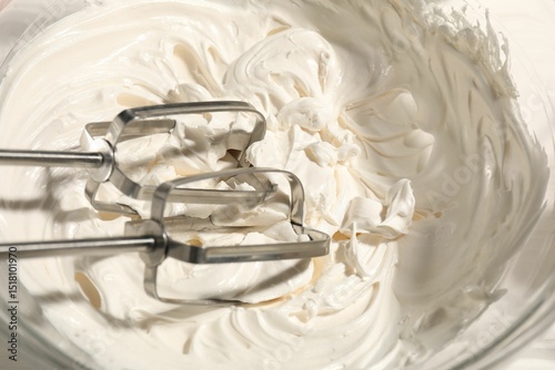 Obraz na plátně Whisks and whipped cream in bowl on table, top view