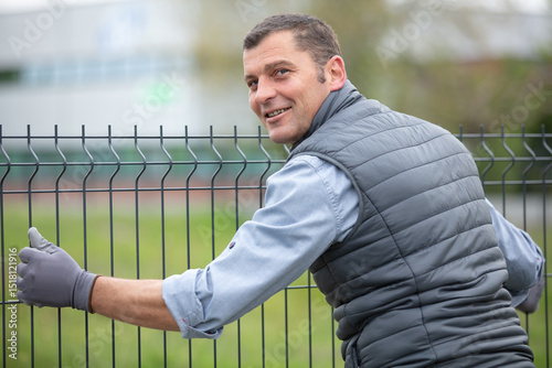 worker installing welded metal mesh fence