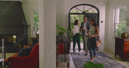 Diverse friends arriving front door hugging hosts, accepting coffee, reviewing dining seating plan