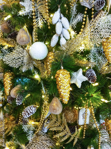 Richly decorated Christmas tree. Golden balls, cones and glowing garlands.