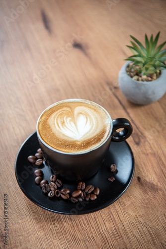 A cozy cup of cappuccino with heart-shaped latte art, resting on a wooden table beside a small succulent—inviting a quiet and peaceful coffee moment. photo