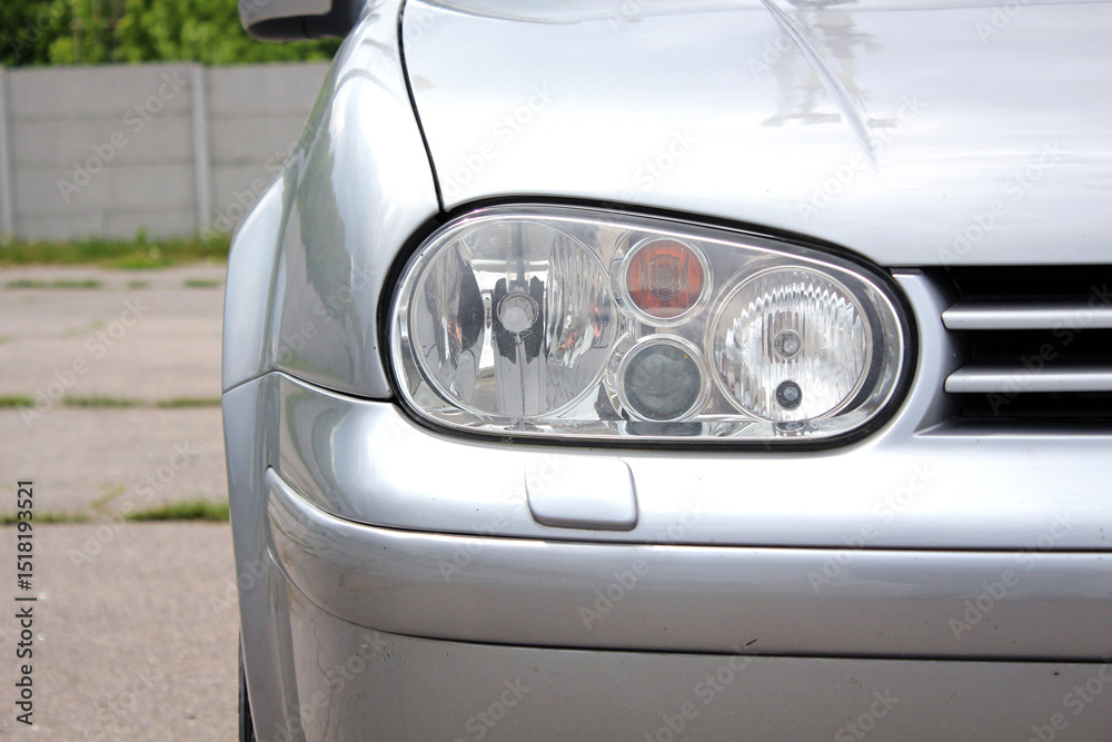 Front right headlight of a classic grey car. Car headlight with headlight washer in bumper. Lamp of modern car headlight. Front right headlight of a classic grey car. Car headlight with headlight washer in bumper. Lamp of modern car headlight.