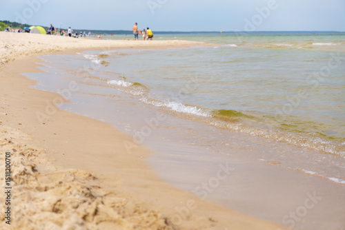 Fototapeta Naklejka Na Ścianę i Meble -  Serene beach view with gentle waves washing onto the sandy shore offers a peaceful escape perfect for summer vacations and relaxation time near the tranquil ocean and Baltic sea